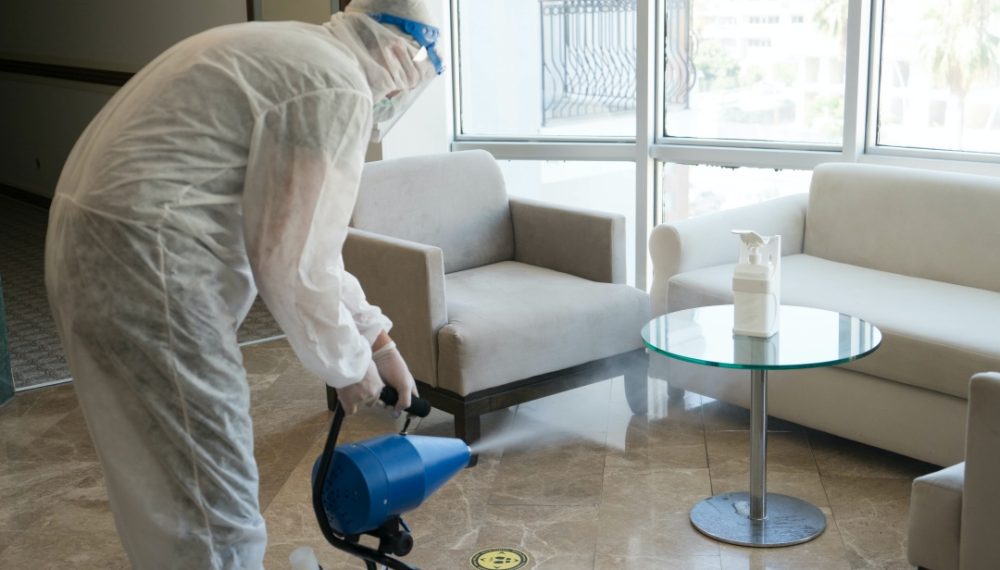Man in white protective suit in the hotel sprays hotel rooms, elevator to prevent the contamination of corona virus.Ulv Cold Fogger machine